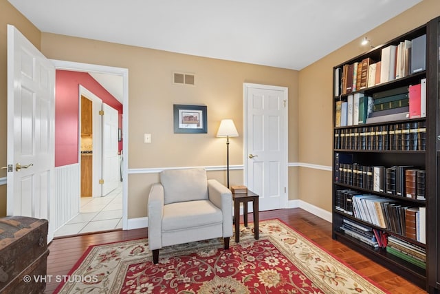 living area featuring baseboards, visible vents, and wood-type flooring