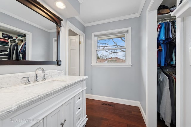 bathroom with visible vents, crown molding, baseboards, wood finished floors, and vanity