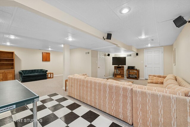 carpeted living area featuring tile patterned floors, visible vents, a paneled ceiling, and baseboards