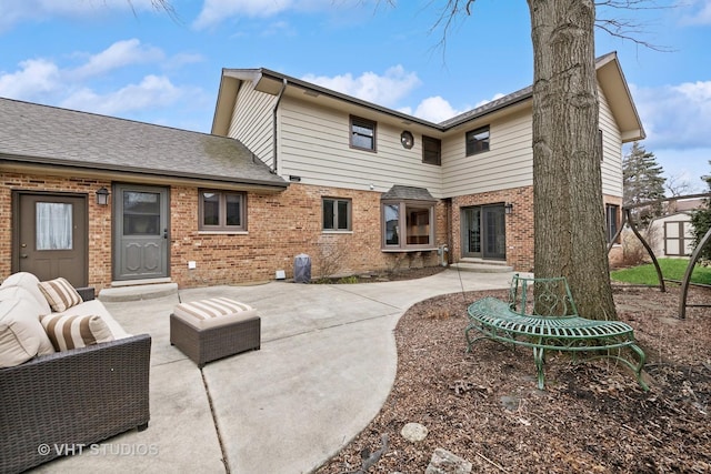 back of house with brick siding, a shed, an outdoor hangout area, a patio area, and an outbuilding