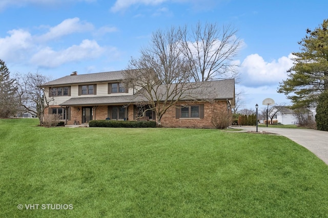 traditional home with a front lawn, concrete driveway, a shingled roof, brick siding, and a chimney