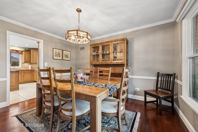 dining space featuring crown molding, baseboards, light wood-type flooring, and a chandelier