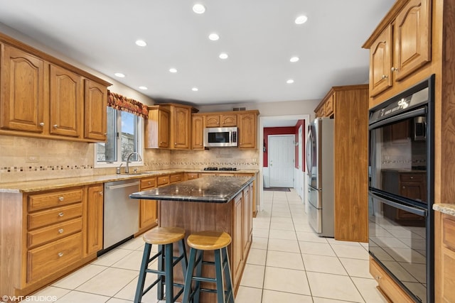 kitchen with light tile patterned floors, a center island, stainless steel appliances, and a sink