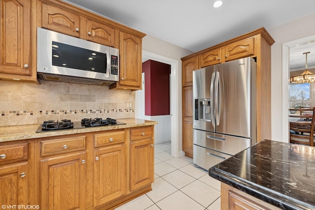 kitchen featuring light tile patterned floors, stainless steel appliances, light stone countertops, and brown cabinets