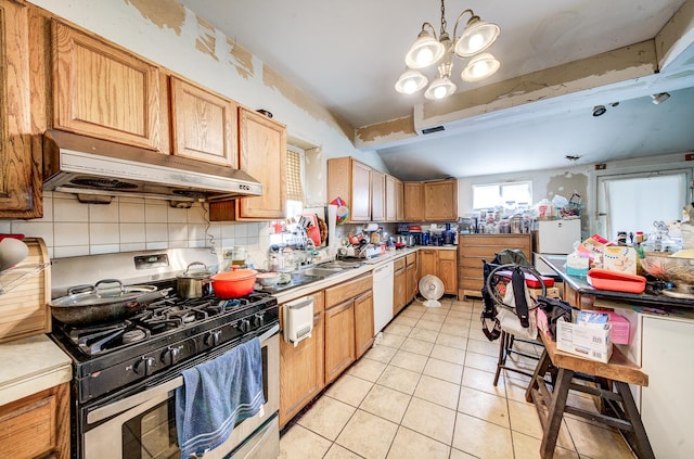 kitchen with sink, light tile patterned floors, backsplash, gas stove, and decorative light fixtures