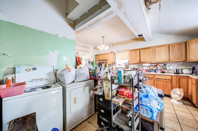 laundry area with light tile patterned floors, washing machine and clothes dryer, and an inviting chandelier