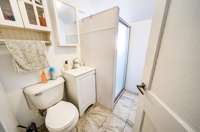 bathroom featuring vanity, a shower with door, and toilet