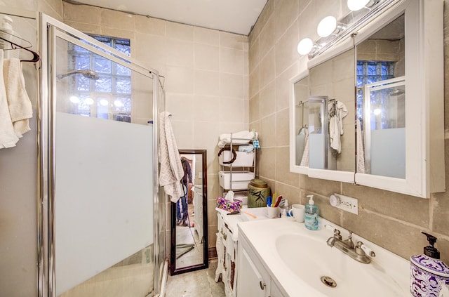 bathroom with vanity, a shower with door, and tile walls