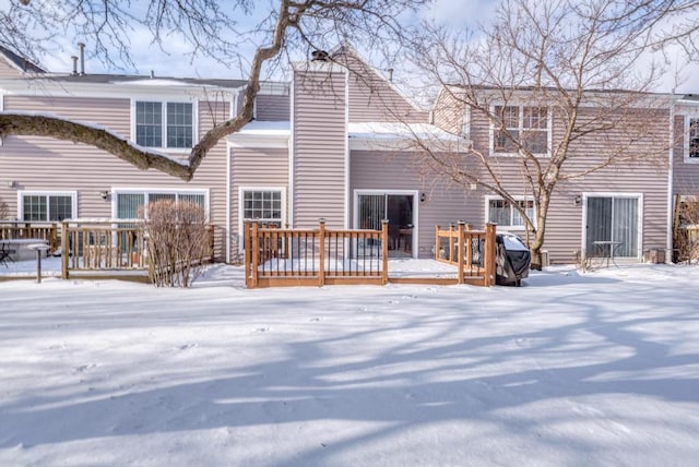 snow covered back of property featuring a wooden deck