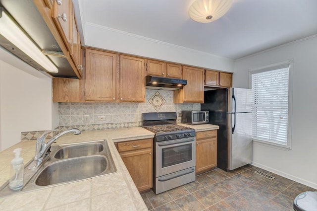 kitchen featuring appliances with stainless steel finishes, sink, backsplash, and ornamental molding