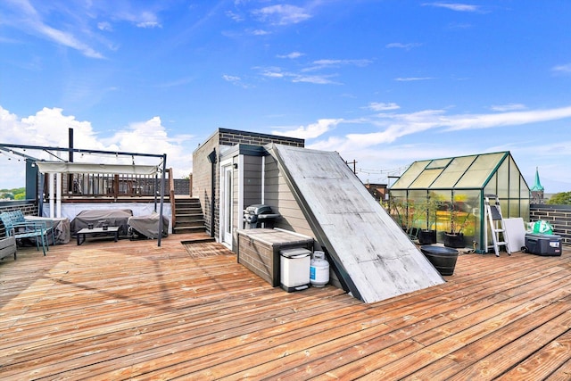 wooden deck featuring an outbuilding, a greenhouse, and a grill