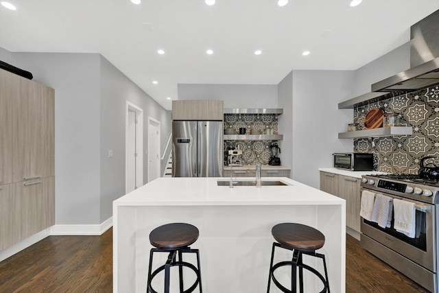 kitchen featuring wall chimney exhaust hood, modern cabinets, stainless steel appliances, a kitchen bar, and a sink