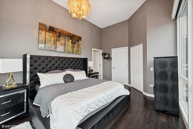 bedroom with a high ceiling, dark wood-type flooring, and an inviting chandelier