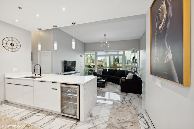 kitchen featuring sink, hanging light fixtures, wine cooler, white cabinets, and kitchen peninsula