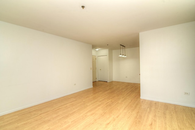 spare room featuring light wood finished floors and baseboards