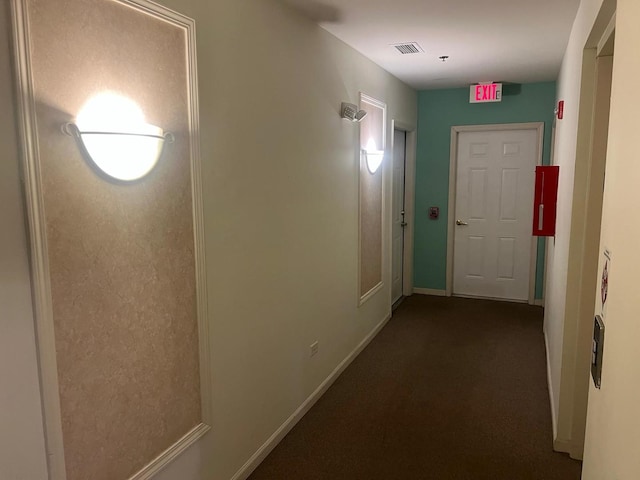 corridor featuring visible vents, dark carpet, and baseboards