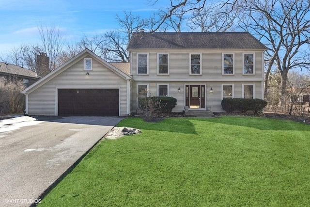 colonial inspired home featuring a front lawn, an attached garage, and aphalt driveway