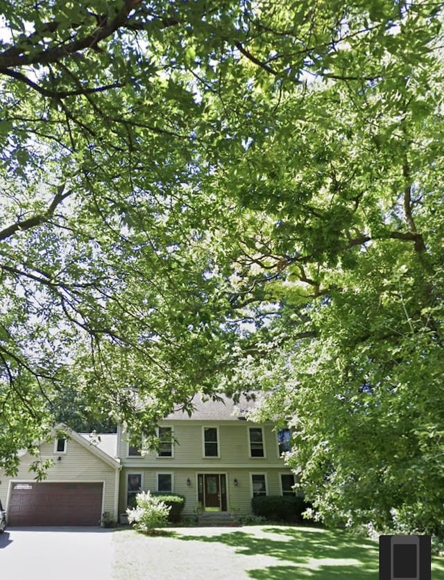 colonial home featuring a front lawn, an attached garage, and aphalt driveway