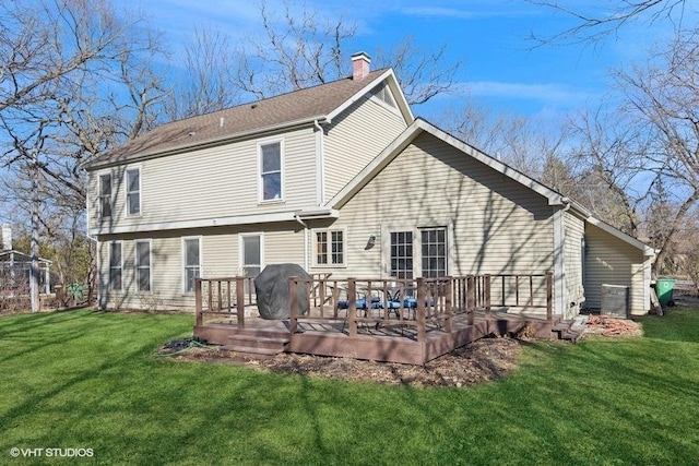 back of property featuring a chimney, a deck, and a lawn