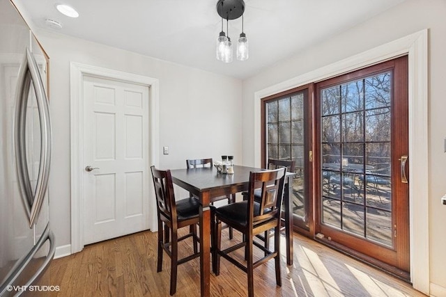 dining space featuring light wood-style flooring and baseboards