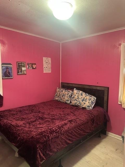 bedroom with wood finished floors and ornamental molding