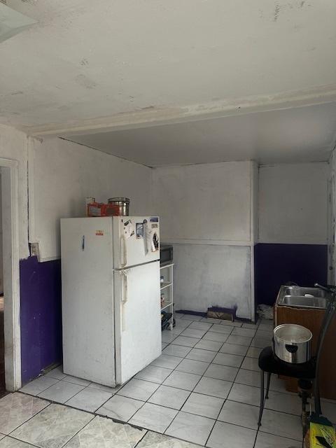 kitchen with a sink, light tile patterned floors, and freestanding refrigerator