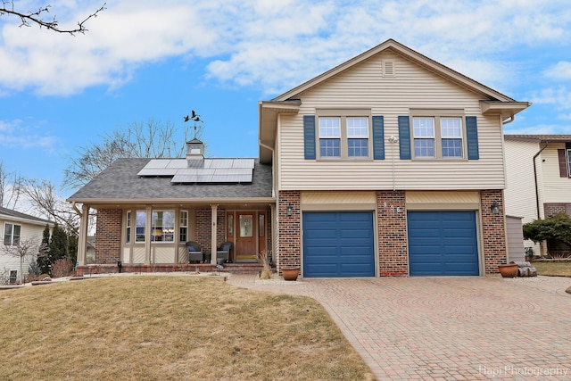 view of front of home featuring decorative driveway, brick siding, a porch, roof mounted solar panels, and a front lawn