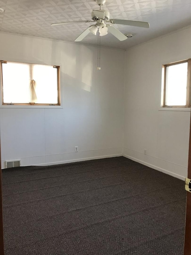 spare room featuring dark colored carpet and ceiling fan