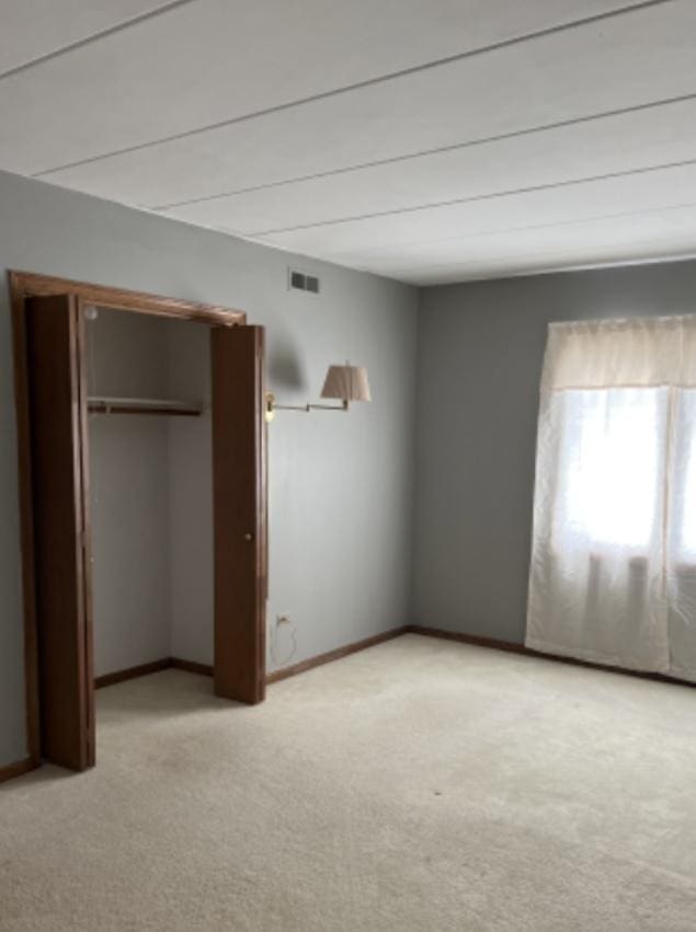 unfurnished bedroom with light carpet and a closet