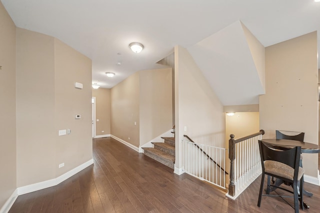 hall with wood-type flooring, an upstairs landing, and baseboards