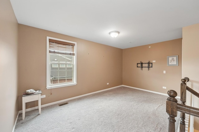 unfurnished room with carpet flooring, visible vents, and baseboards