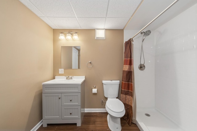 full bath featuring toilet, a tile shower, vanity, wood finished floors, and a drop ceiling