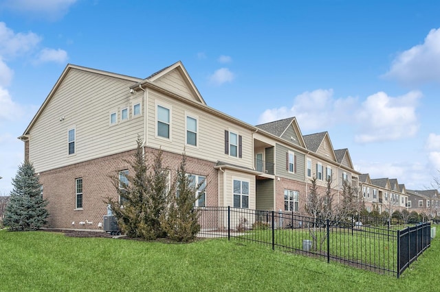 exterior space with central AC unit, a residential view, fence, a yard, and brick siding