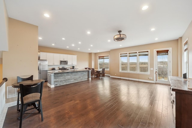 kitchen featuring stainless steel appliances, visible vents, white cabinetry, dark wood-style floors, and a center island with sink