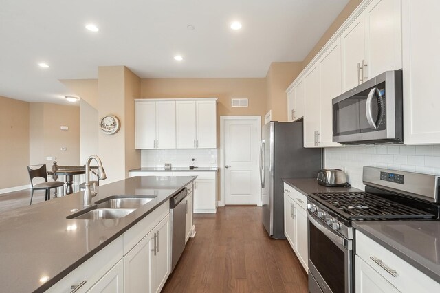 kitchen featuring dark countertops, visible vents, appliances with stainless steel finishes, white cabinetry, and a sink