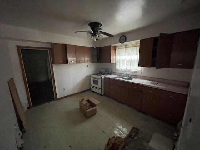 kitchen with white gas range, dark brown cabinets, sink, and ceiling fan