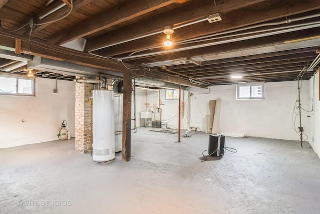 basement featuring sink, plenty of natural light, and water heater