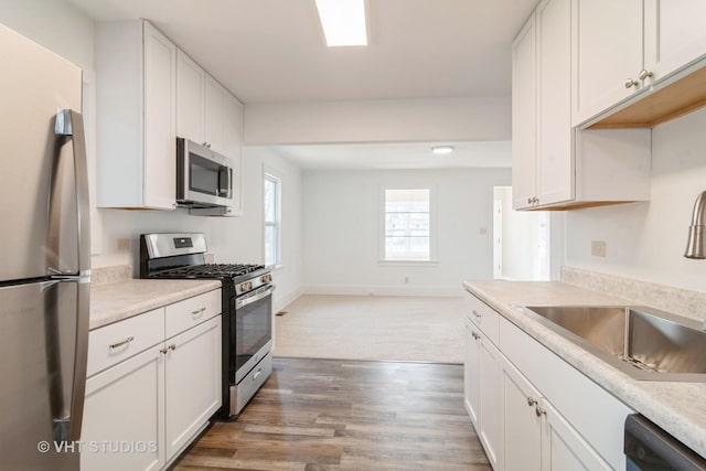 kitchen with stainless steel appliances, sink, dark wood-type flooring, and white cabinets