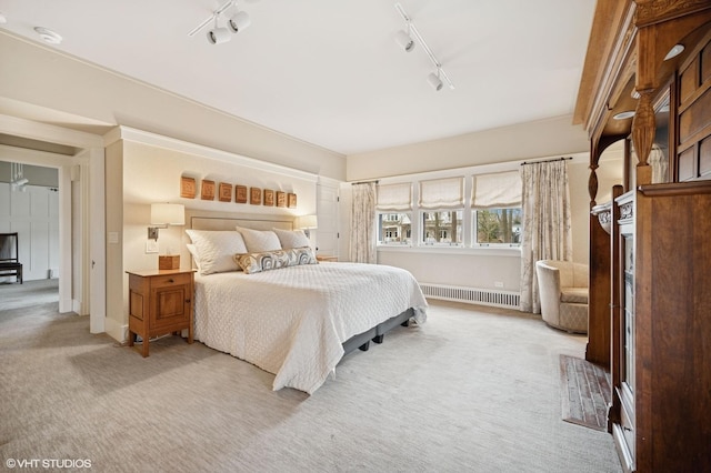 carpeted bedroom featuring track lighting and radiator heating unit