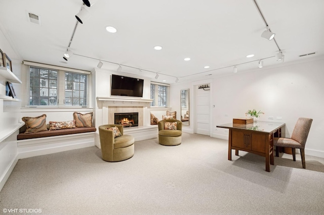 living room featuring rail lighting, light colored carpet, recessed lighting, and a lit fireplace