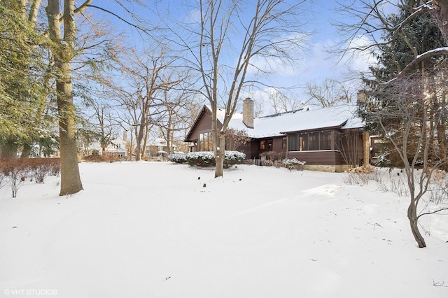 yard layered in snow featuring a sunroom