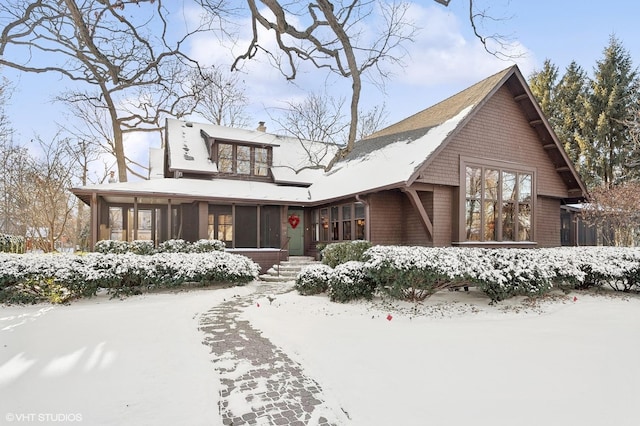 view of front of home with a chimney and a sunroom