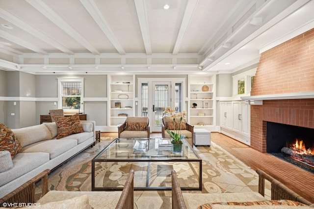 living area with beam ceiling, a brick fireplace, plenty of natural light, and built in shelves