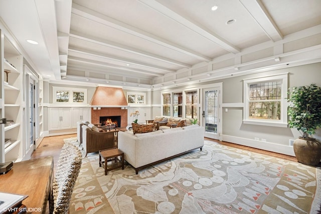 living area featuring baseboards, beam ceiling, light wood-style flooring, recessed lighting, and a fireplace