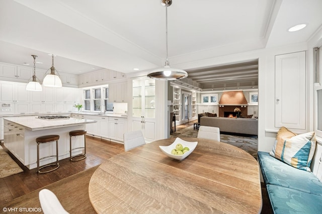 dining area featuring recessed lighting, a lit fireplace, and dark wood finished floors