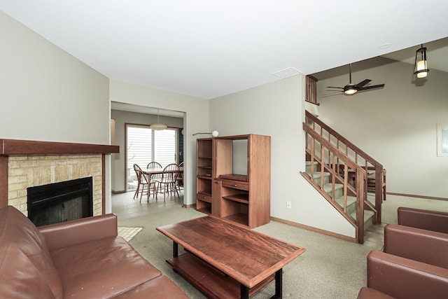 living area with ceiling fan, carpet flooring, baseboards, stairs, and a brick fireplace