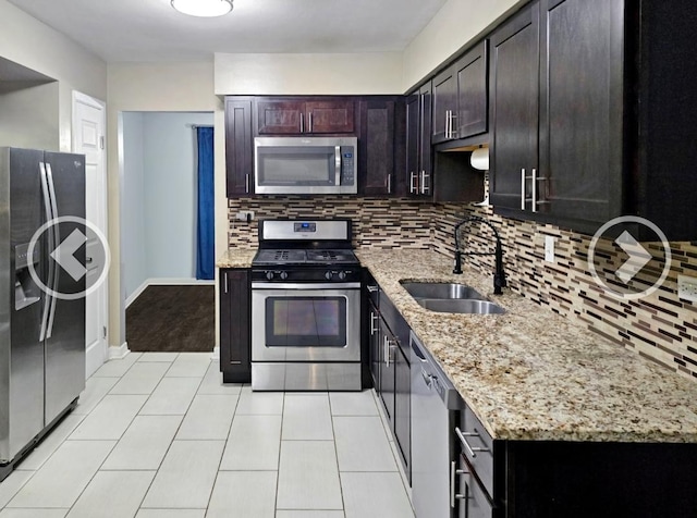 kitchen featuring tasteful backsplash, sink, dark brown cabinetry, stainless steel appliances, and light stone countertops