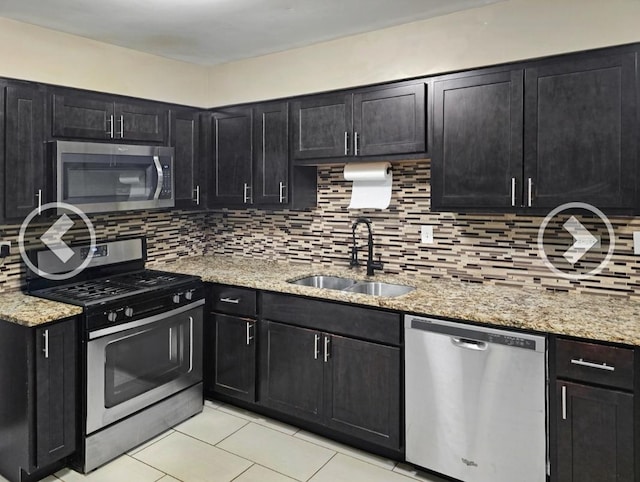 kitchen featuring stainless steel appliances, light stone countertops, sink, and decorative backsplash