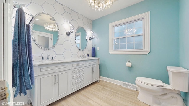 bathroom with hardwood / wood-style floors, tasteful backsplash, vanity, toilet, and an inviting chandelier