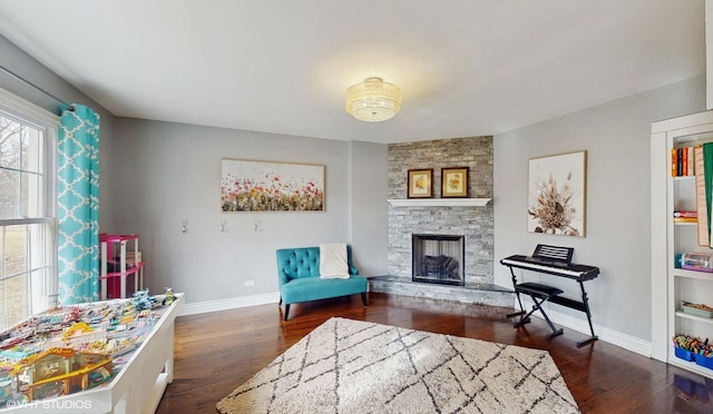 sitting room featuring dark hardwood / wood-style flooring and a stone fireplace